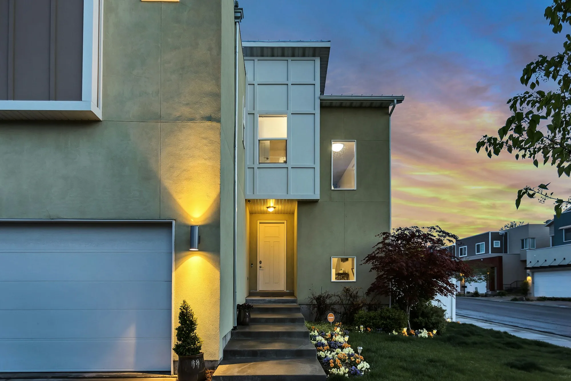 Modern home with lit front steps and an attached garage
