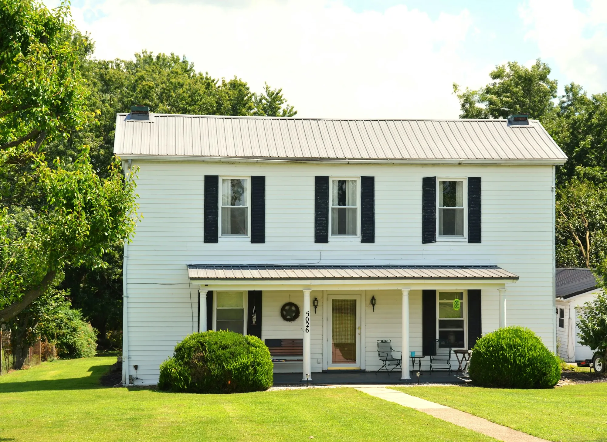 White colonial home with black shutters and a front walk