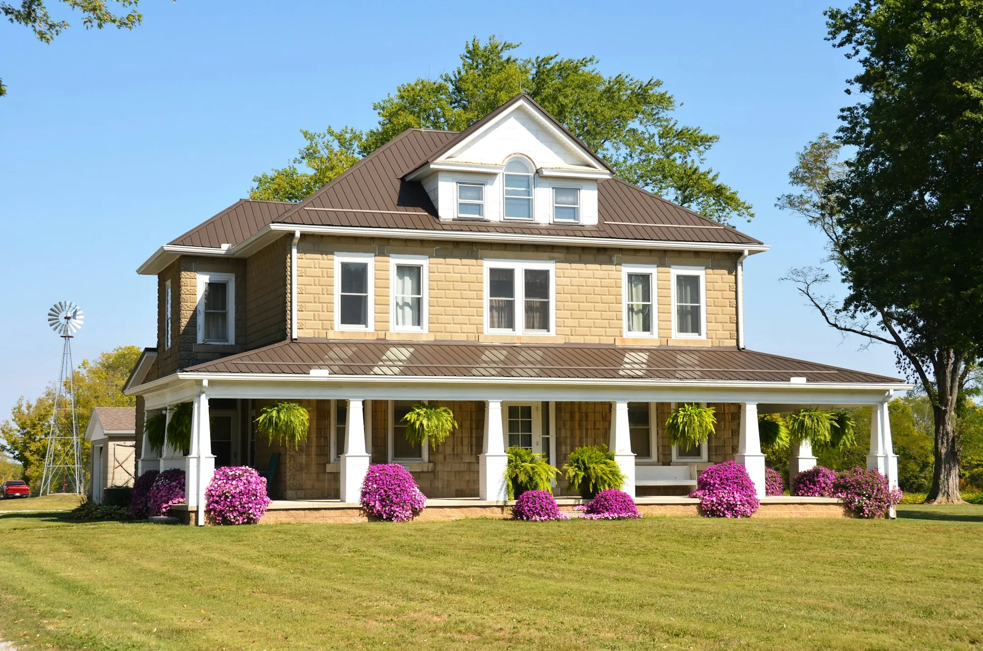 Yellow home with a wide front porch and flowers
